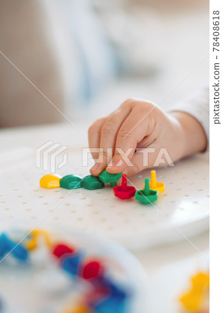 The child sticks the mosaic into the shape with his fingers 78408618