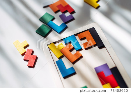 Wooden colored puzzle lies scattered on the table 78408620