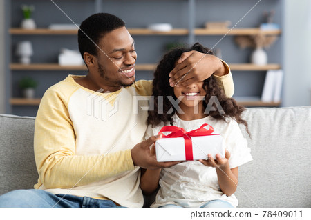 Loving black dad giving present his cute daughter Loving black dad giving present his cute daughter 78409011