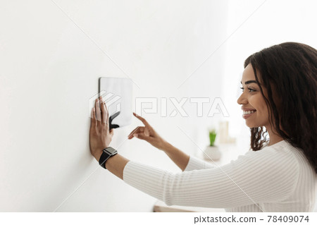 African american woman using digital tablet with blank screen on wall with smart home control system app 78409074