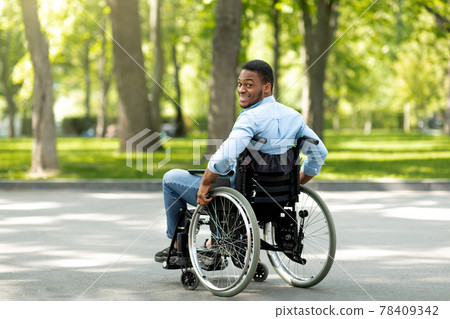 Joyful handicapped black man in wheelchair spending time at city park, full length Joyful handicapped black man in wheelchair spending time at city park, full length 78409342