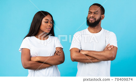 Offended black couple standing with crossed arms, blue studio wall 78409874