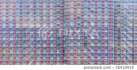 Side view of building under construction covered by net. Side view of building under construction covered by net. 78410919