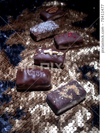 Assorted dark handmade chocolate on the sequins Assorted dark handmade chocolate on the sequins 78411477