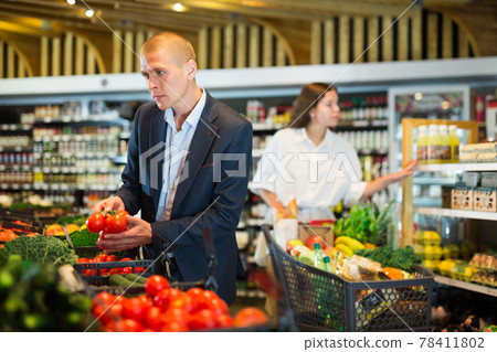 Young confident man selects fresh vegetables in the supermarket 78411802