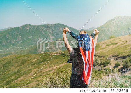 Man with child on his neck, boy on his back has an American flag on the background of nature Man with child on his neck, boy on his back has an American flag on the background of nature 78412296