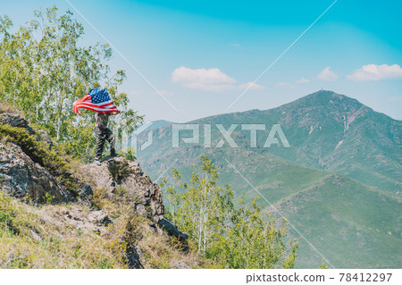 On rock, man in military uniform holding an American flag On rock, man in military uniform holding an American flag 78412297