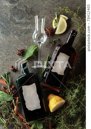 Vintage bottles of gin and various ingredients on an old stone table. 78412405