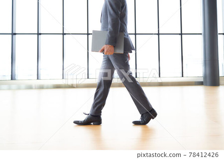 一個帶著筆記本電腦走路的商人 78412426