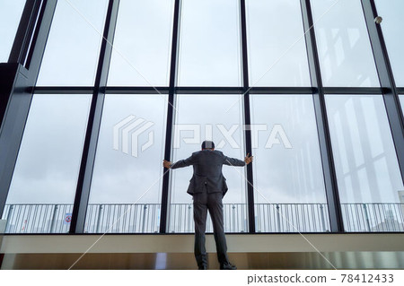 Back view of a businessman looking down with his hand on the window 78412433