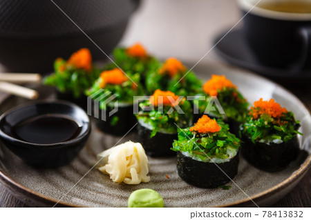 Sushi maki rolls with crab, seaweed salad and flying fish roe on a plate with chopsticks, soy sauce, wasabi and ginger. Japanese traditional seafood served for lunch in modern gourmet restaurant Sushi maki rolls with crab, seaweed salad and flying fish roe on a plate with chopsticks, soy sauce, wasabi and ginger. Japanese traditional seafood served for lunch in modern gourmet restaurant 78413832