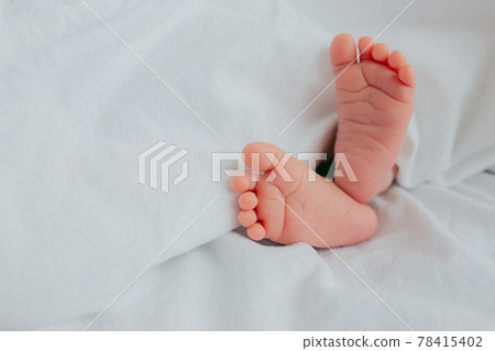 Baby's feet under a white blanket Baby's feet under a white blanket 78415402