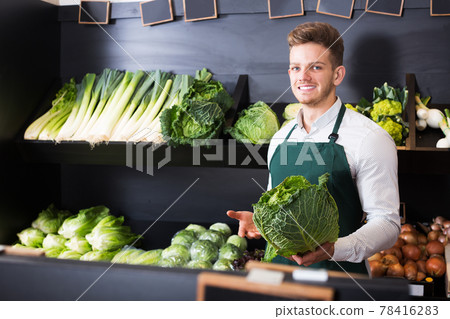 Seller showing cabbage in shop Seller showing cabbage in shop 78416283