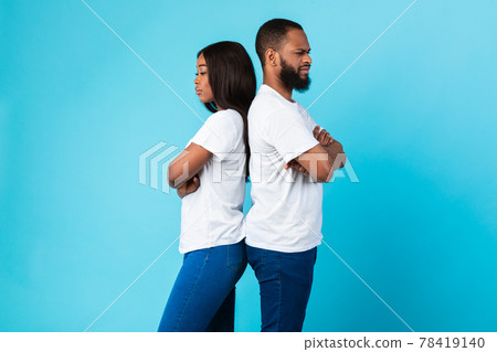 Black couple standing back to back, blue studio wall 78419140