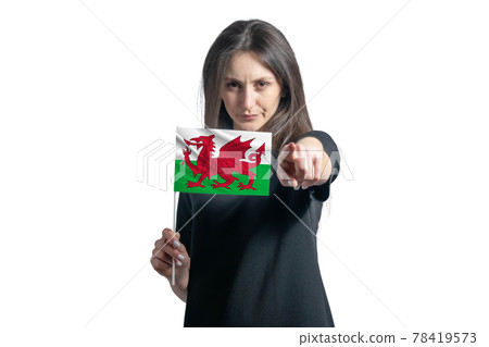 Happy young white woman holding flag of Wales and points forward in front of him isolated on a white background Happy young white woman holding flag of Wales and points forward in front of him isolated on a white background 78419573