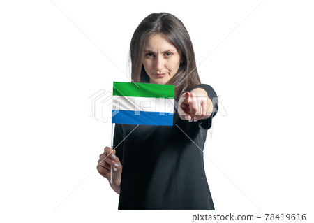 Happy young white woman holding flag of Sierra Leone and points forward in front of him isolated on a white background Happy young white woman holding flag of Sierra Leone and points forward in front of him isolated on a white background 78419616