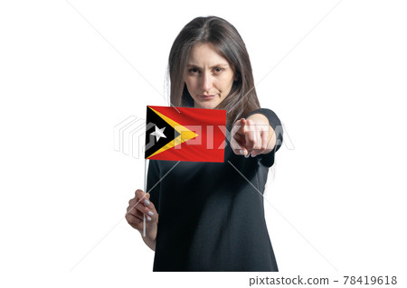 Happy young white woman holding flag of East Timor and points forward in front of him isolated on a white background Happy young white woman holding flag of East Timor and points forward in front of him isolated on a white background 78419618