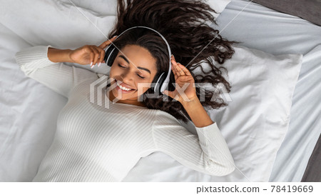Satisfied young African American woman listening to music Satisfied young African American woman listening to music 78419669