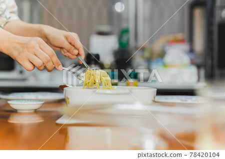 Woman eating creamy spaghetti carbonara with folk and spoon at dinner table. Woman eating creamy spaghetti carbonara with folk and spoon at dinner table. 78420104