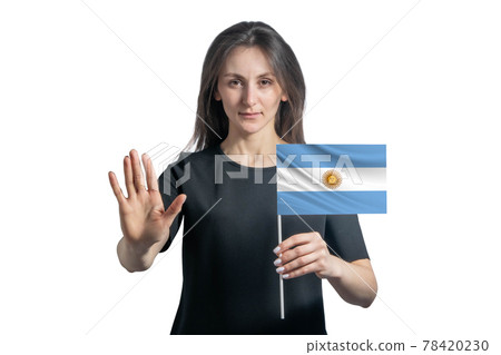 Happy young white woman holding flag of Argentina and with a serious face shows a hand stop sign isolated on a white background 78420230