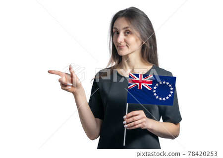 Happy young white woman holding flag Cook Islands and points to the left isolated on a white background 78420253
