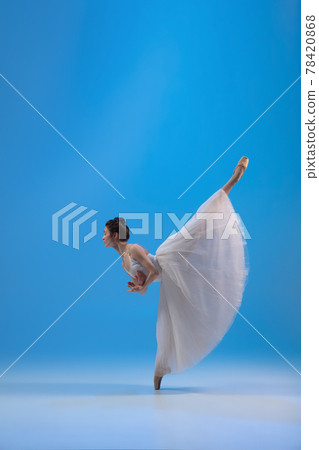 Young and incredibly beautiful ballerina is posing and dancing at blue studio full of light. 78420868