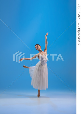 Young and incredibly beautiful ballerina is posing and dancing at blue studio full of light. 78420872
