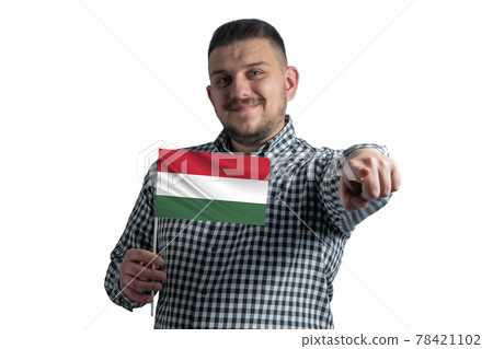 White guy holding a flag of Hungary and points forward in front of him isolated on a white background White guy holding a flag of Hungary and points forward in front of him isolated on a white background 78421102