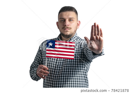 White guy holding a flag of Liberia and with a serious face shows a hand stop sign isolated on a white background White guy holding a flag of Liberia and with a serious face shows a hand stop sign isolated on a white background 78421878