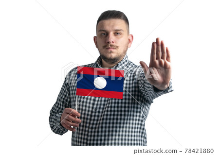 White guy holding a flag of Laos and with a serious face shows a hand stop sign isolated on a white background 78421880