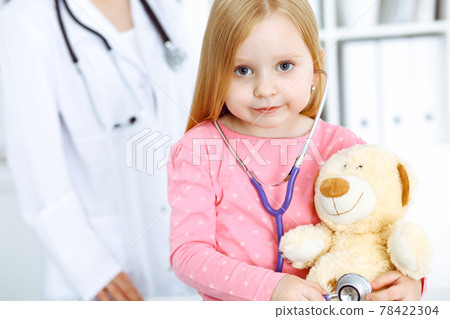 Happy smiling female kid-patient at usual medical inspection. Doctor and young girl in the clinic. Medicine, healthcare concepts Happy smiling female kid-patient at usual medical inspection. Doctor and young girl in the clinic. Medicine, healthcare concepts 78422304