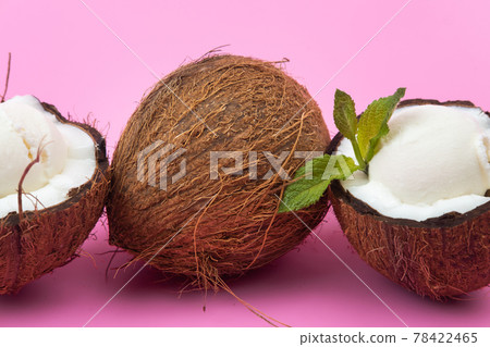 Vanilla ice cream balls in fresh coconut halves decorated with mint leaves on a pink background Vanilla ice cream balls in fresh coconut halves decorated with mint leaves on a pink background 78422465