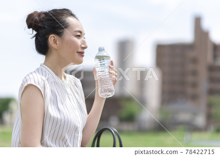 Woman drinking water outdoors Woman drinking water outdoors 78422715