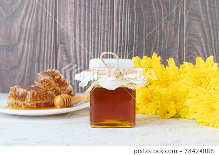 Fresh honey bottle with organic honeycomb and wild flower on wooden table. Healthy food concept. 78424088
