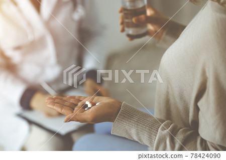Close-up woman-patient holding pills near her doctor, time to take medications for headache. Stay at home concept during Coronavirus pandemic and self isolation quarantine. Covid 2019 78424090