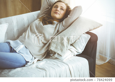 Happy blond woman put hands behind head sitting leaned on couch caucasian female enjoy lazy weekend or vacation in sunny living room Happy blond woman put hands behind head sitting leaned on couch caucasian female enjoy lazy weekend or vacation in sunny living room 78424099
