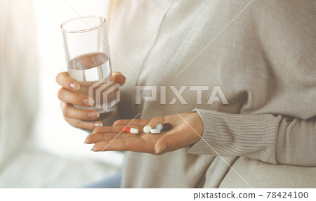 Close-up woman holding pills time to take medications, cure for headache. Medicine concept during self isolation and Coronavirus pandemic Close-up woman holding pills time to take medications, cure for headache. Medicine concept during self isolation and Coronavirus pandemic 78424100