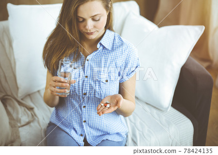 Young woman holding pills time to take medications, cure for headache, high blood pressure or cholesterol level remedy pain killer drugs Young woman holding pills time to take medications, cure for headache, high blood pressure or cholesterol level remedy pain killer drugs 78424135