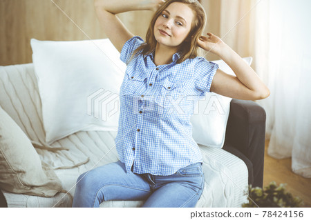Happy brunette woman put hands behind head sitting leaned on couch, european female stretching and enjoying lazy weekend or vacation in cozy living room 78424156