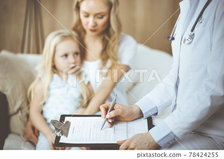 Doctor and patient. Pediatrician using clipboard while examining little girl with her mother at home. Sick and unhappy child at medical exam. Medicine concept 78424255