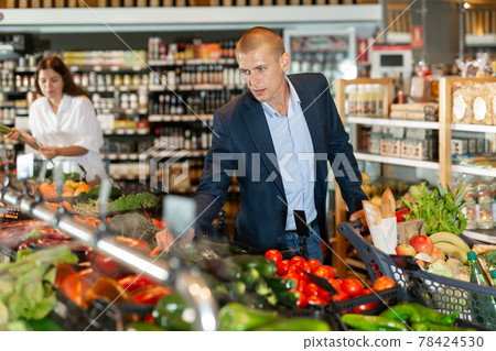 Man shopping at vegetables department of supermarket 78424530