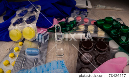 Coloured pills and sterile medical tools surround vial Coloured pills and sterile medical tools surround vial 78426257
