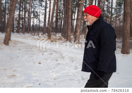 Bearded pensioner in red hat walks along forestry path Bearded pensioner in red hat walks along forestry path 78426318