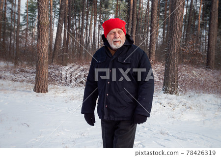 Bearded pensioner in red hat walks along forestry path Bearded pensioner in red hat walks along forestry path 78426319
