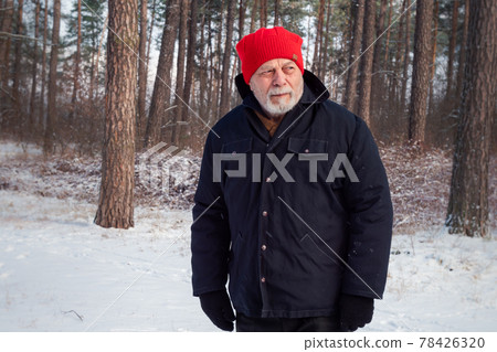 Serious gamekeeper in red hat wanders along forest path 78426320
