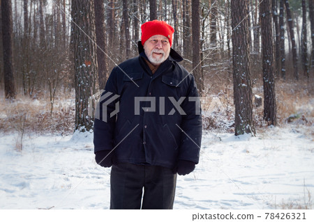 Serious gamekeeper in red hat wanders along forest path Serious gamekeeper in red hat wanders along forest path 78426321