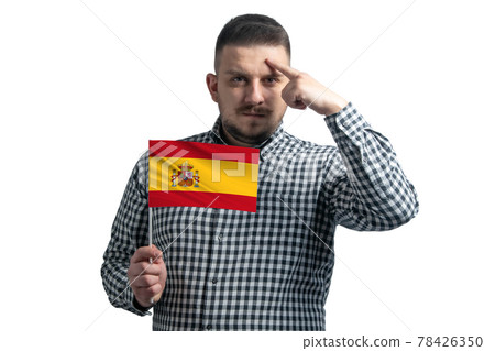 White guy holding a flag of Spain and a finger touches the temple on the head isolated on a white background White guy holding a flag of Spain and a finger touches the temple on the head isolated on a white background 78426350