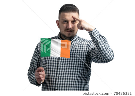 White guy holding a flag of Ireland and a finger touches the temple on the head isolated on a white background White guy holding a flag of Ireland and a finger touches the temple on the head isolated on a white background 78426351