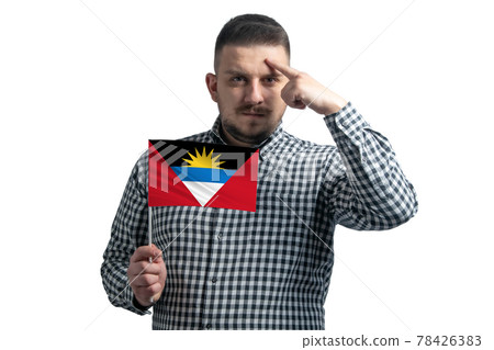 White guy holding a flag of Antigua and Barbuda and a finger touches the temple on the head isolated on a white background White guy holding a flag of Antigua and Barbuda and a finger touches the temple on the head isolated on a white background 78426383
