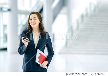 經營一部智能手機的女商人在辦公室 經營一部智能手機的女商人在辦公室 78426763